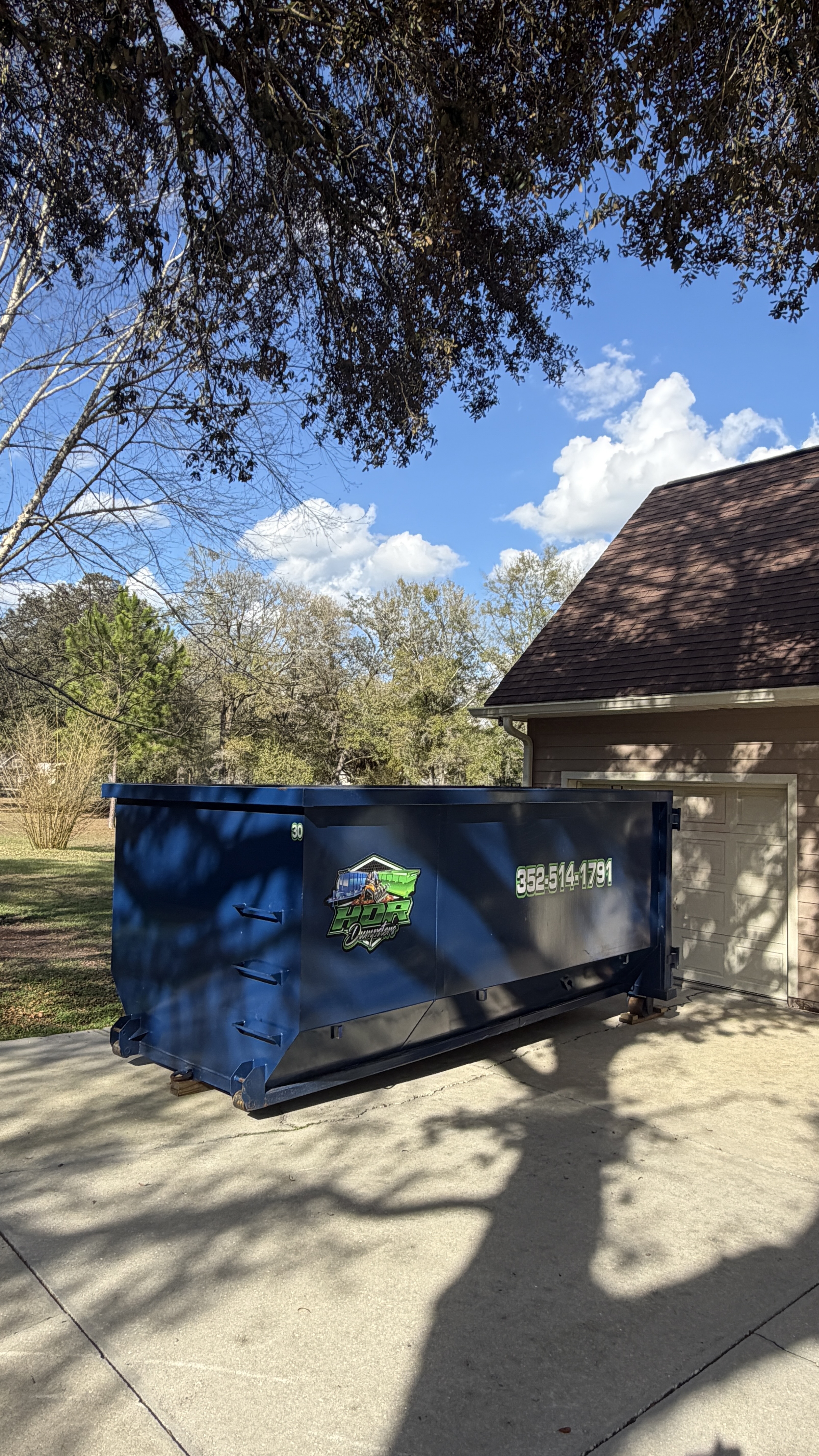 15-yard HDR Dumpster delivered on a residential driveway under a shade tree