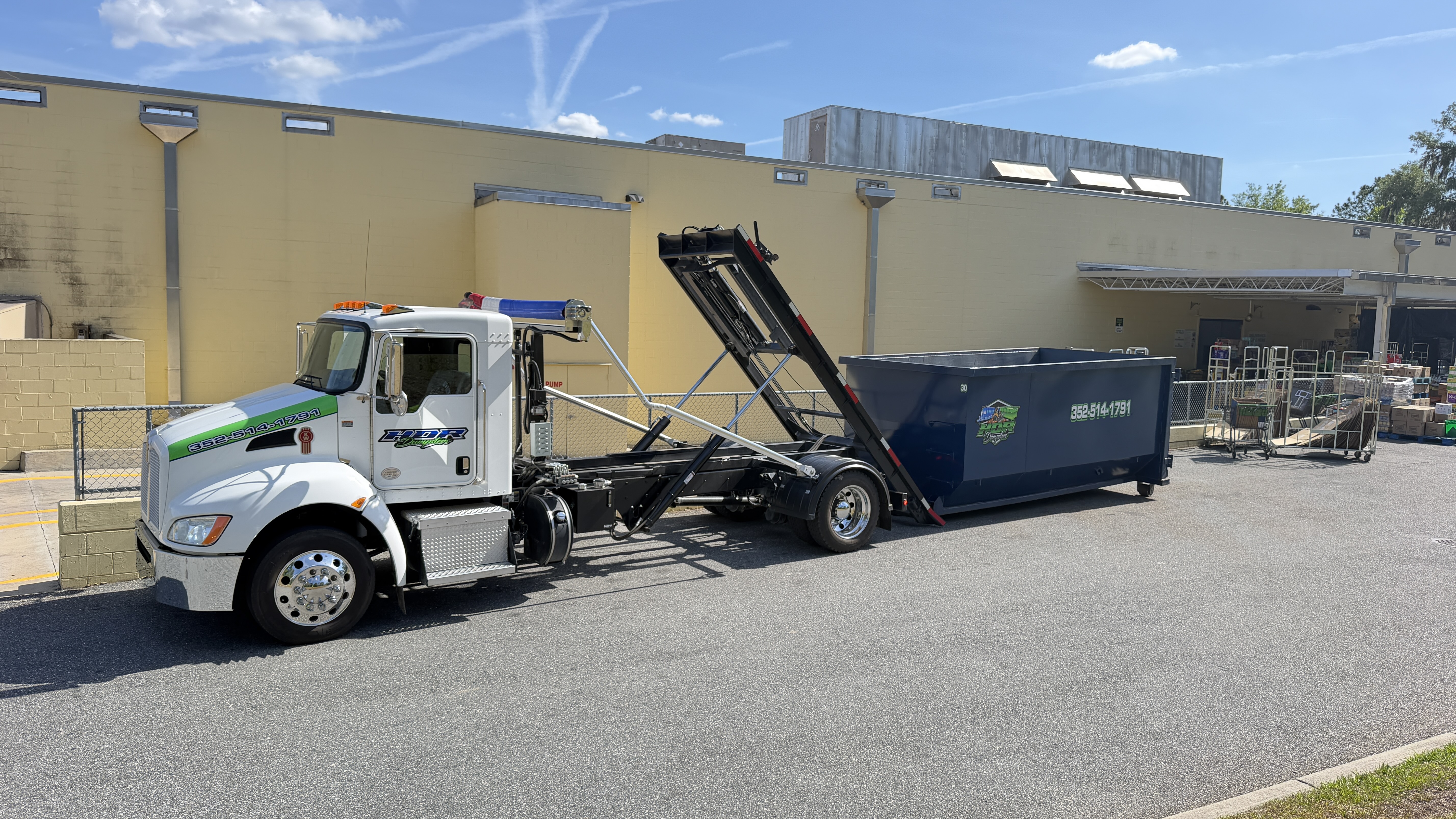 HDR Dumpsters truck rolling off a 20-yard dumpster at a commercial site
